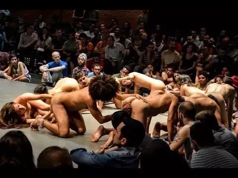 Cena da peça de teatro “Macaquinhos”, em que os atores rastejam em círculo enfiando o dedo no ânus de quem está à frente